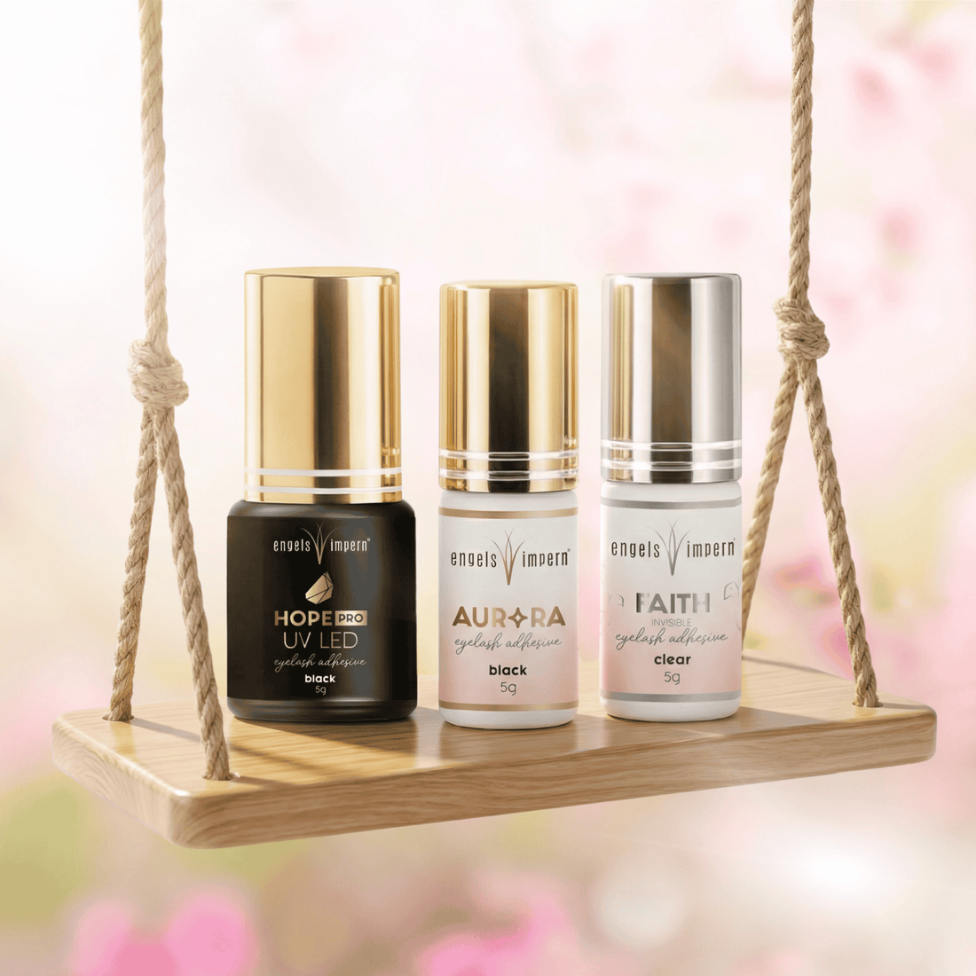 EngelsWimpern Wimpernkleber Hope Pro UV LED, Aurora Black und Faith Clear im Frühlingsdesign auf Holzschaukel